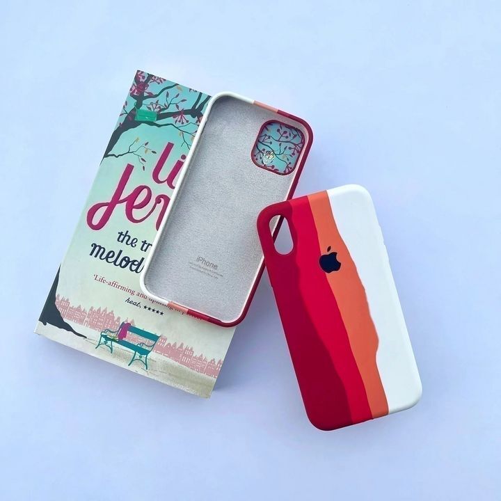  کاور سیلیکونی رنگین کمانی برای گوشی موبایل اپل iPhone 11 Pro Max، با طیف رنگی متنوع در پس‌زمینه کتابی روی میز سفید 