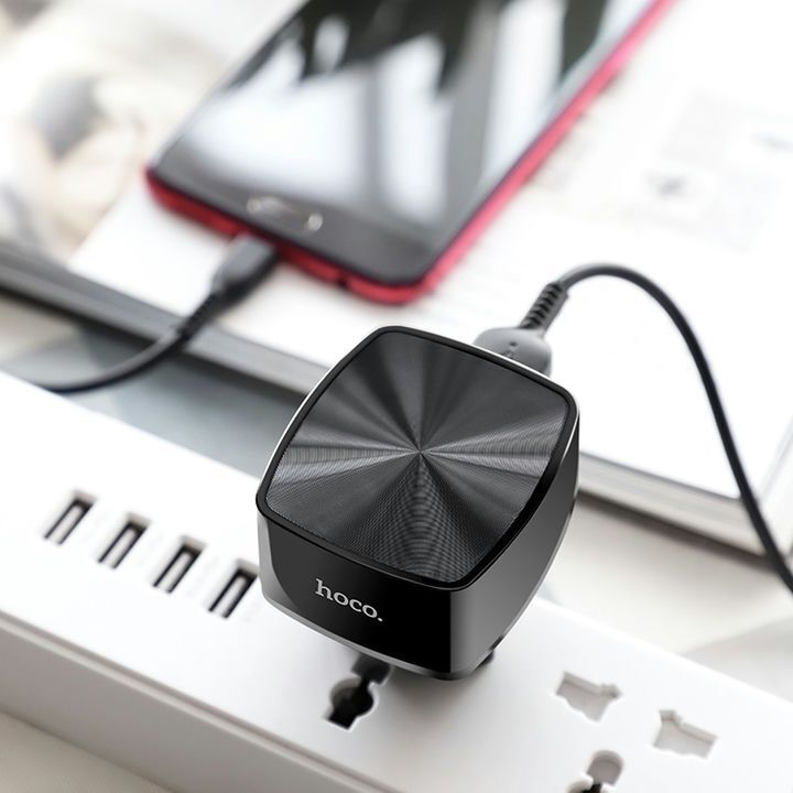شارژر دیواری هوکو مدل C70A مشکی رنگ به همراه کابل Micro USB در حال اتصال به پریز برق