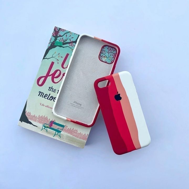 کاور سیلیکونی رنگین کمانی مناسب برای گوشی موبایل اپل iPhone 12 / 12 PRO با طرح رنگهای مختلف در کنار یک کتاب