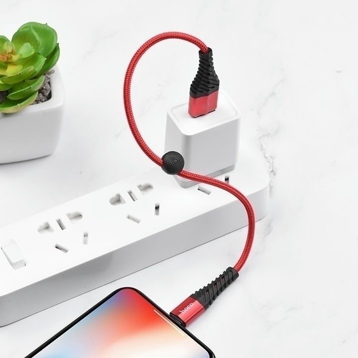  کابل تبدیل USB به لایتنینگ هوکو مدل X38، طول 0.25 متر، متصل به آداپتور و گوشی روی میز سفید 