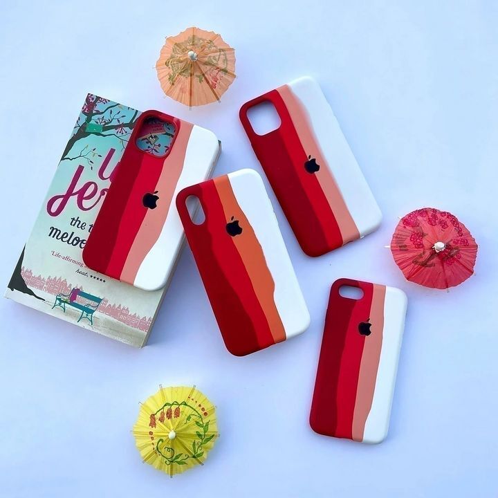  کاور سیلیکونی رنگین کمانی برای گوشی اپل iPhone 11 Pro Max در رنگ‌های قرمز و سفید روی یک کتاب و چترهای تزیینی 